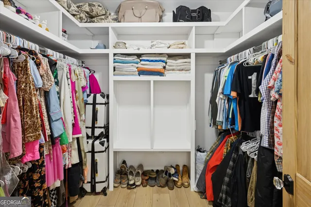 a view of walk in closet with clothes and shoes