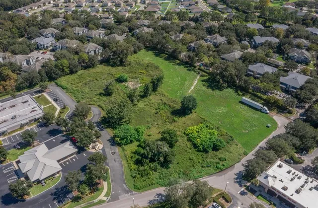 an aerial view of a residential houses with outdoor space and trees