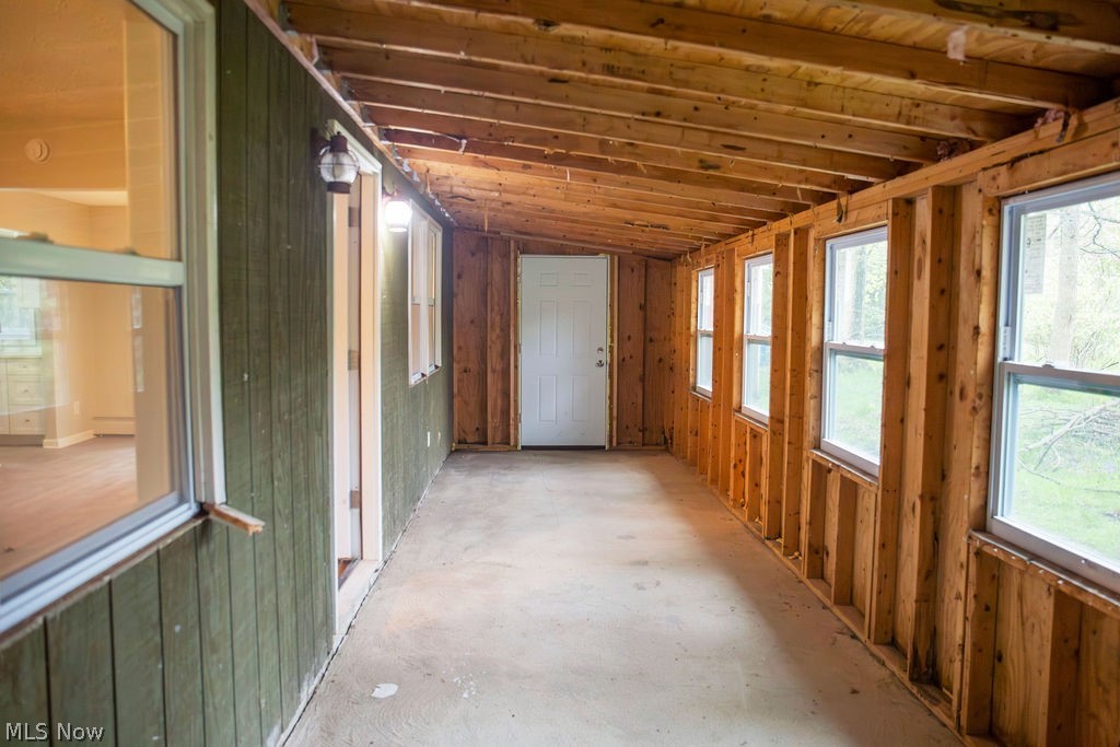 3644 Padanarum Road Geneva, OH 44041 - Photo 7 of 19 Enclosed porch featuring exposed wood framing, concrete flooring, exterior-grade wall paneling, multiple windows, and a white entry door