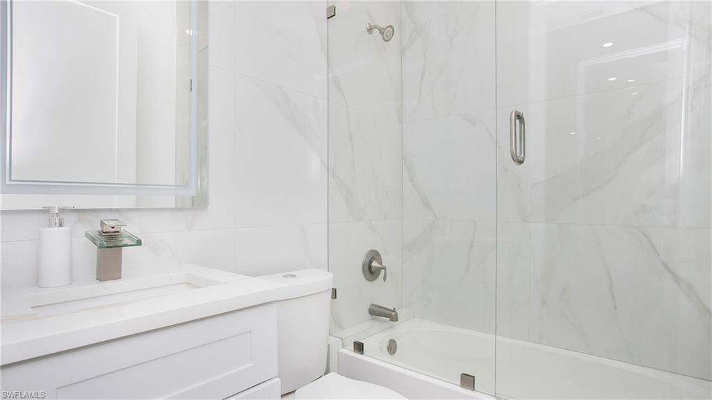 2343 Oil Well Road Naples, FL 34120 - Photo 40 of 46 White bathroom featuring a glass-enclosed tub and shower combination