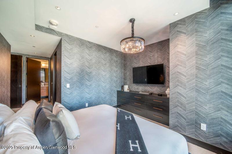 77 Wood Road, Unit 303 Snowmass Village, CO 81615 - Photo 13 of 43 a spacious bedroom with a bed and a flat screen tv