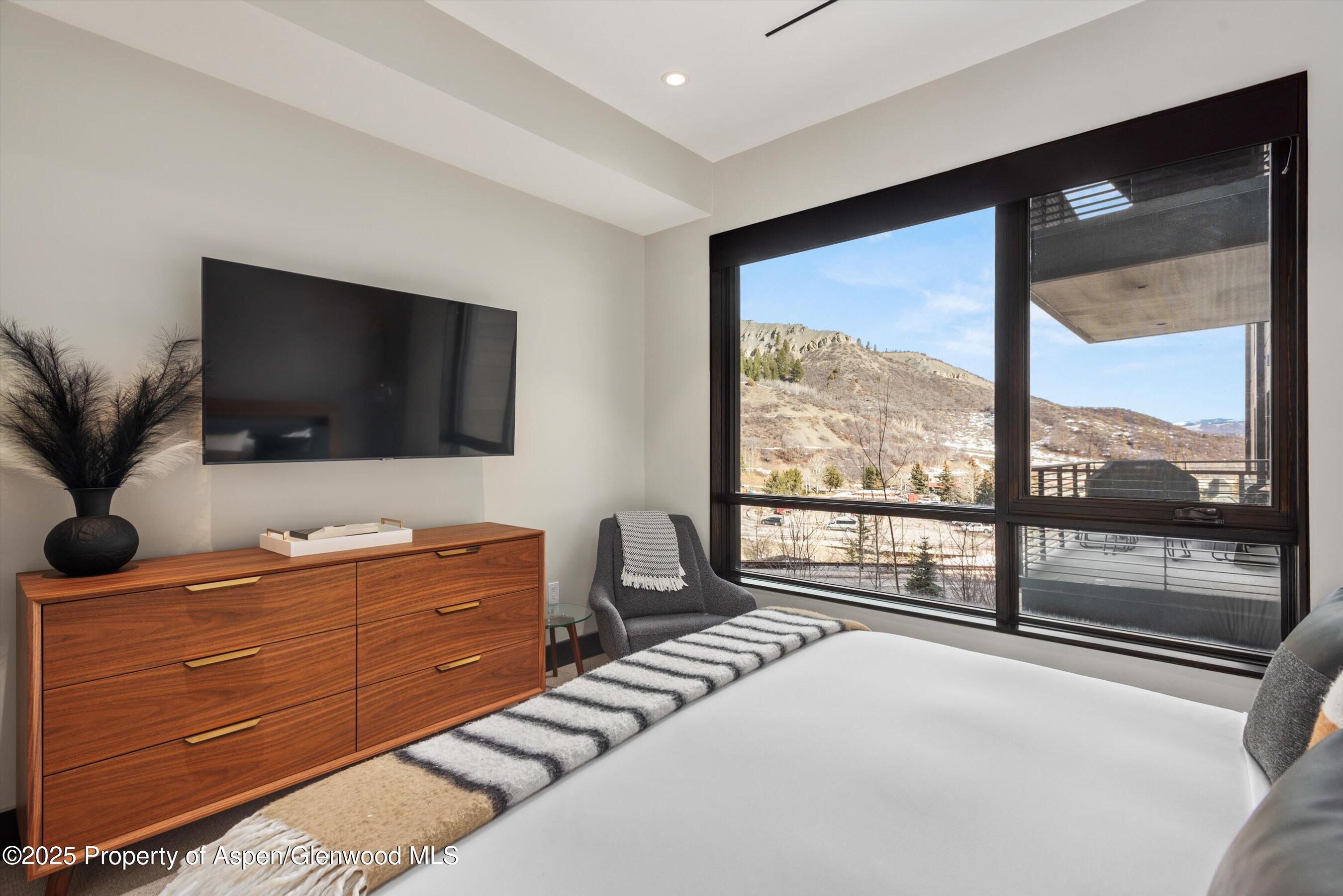 77 Wood Road, Unit 303 Snowmass Village, CO 81615 - Photo 19 of 43 a livingroom with a large window and a flat screen tv