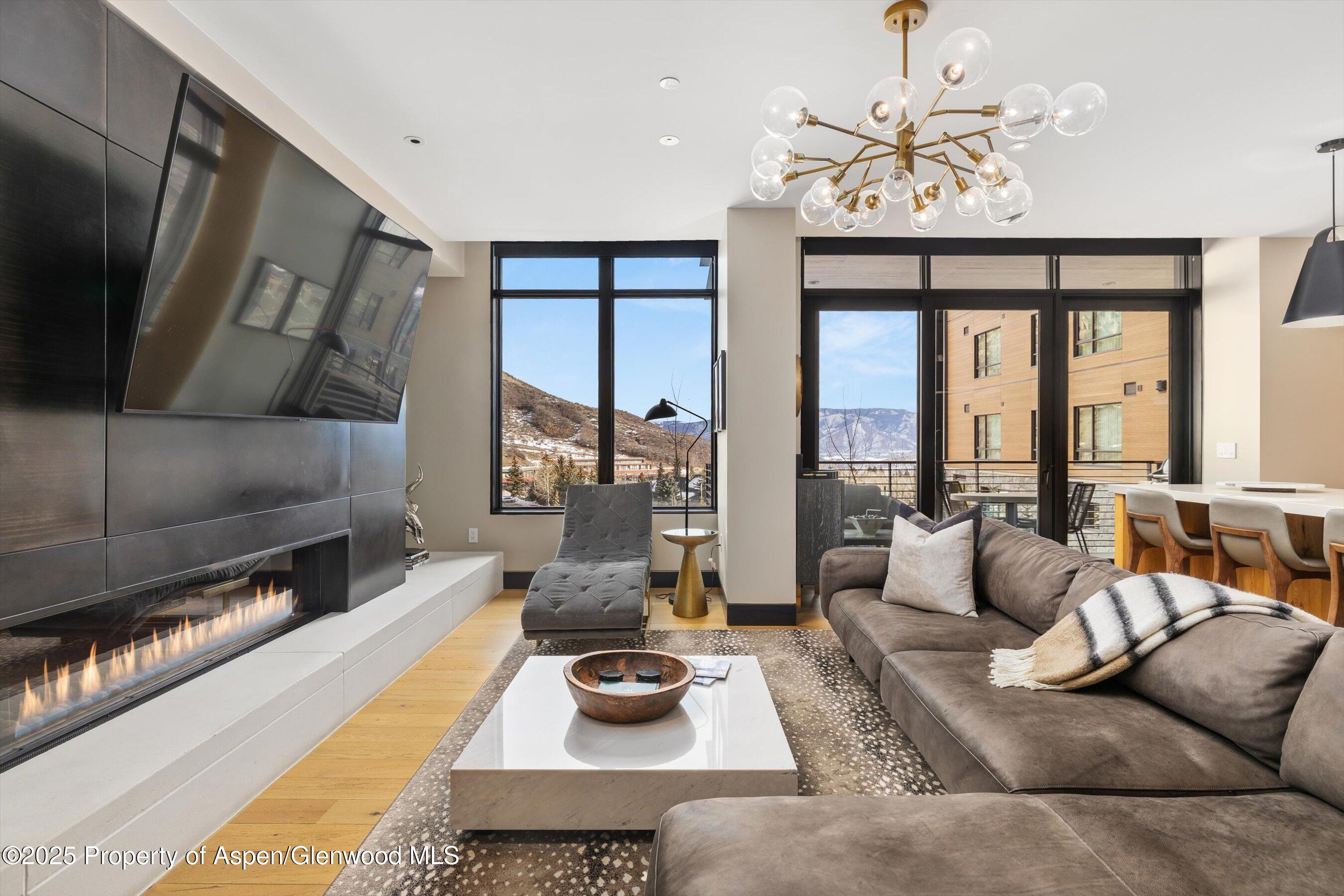 77 Wood Road, Unit 303 Snowmass Village, CO 81615 - Photo 2 of 43 a living room with furniture wooden floor and a chandelier