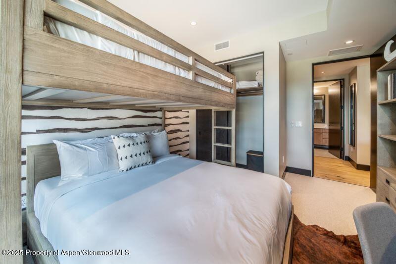 77 Wood Road, Unit 303 Snowmass Village, CO 81615 - Photo 23 of 43 a bedroom with a large bed and a chandelier