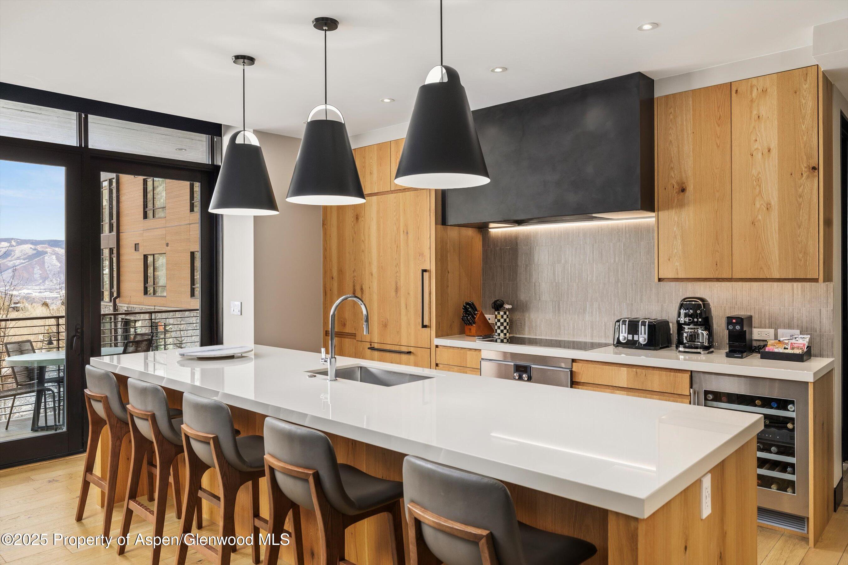 77 Wood Road, Unit 303 Snowmass Village, CO 81615 - Photo 10 of 43 a kitchen with a table chairs sink and cabinets