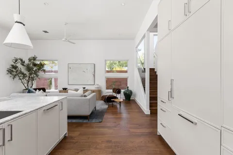 a large white kitchen with a granite countertop sink a window and stainless steel appliances