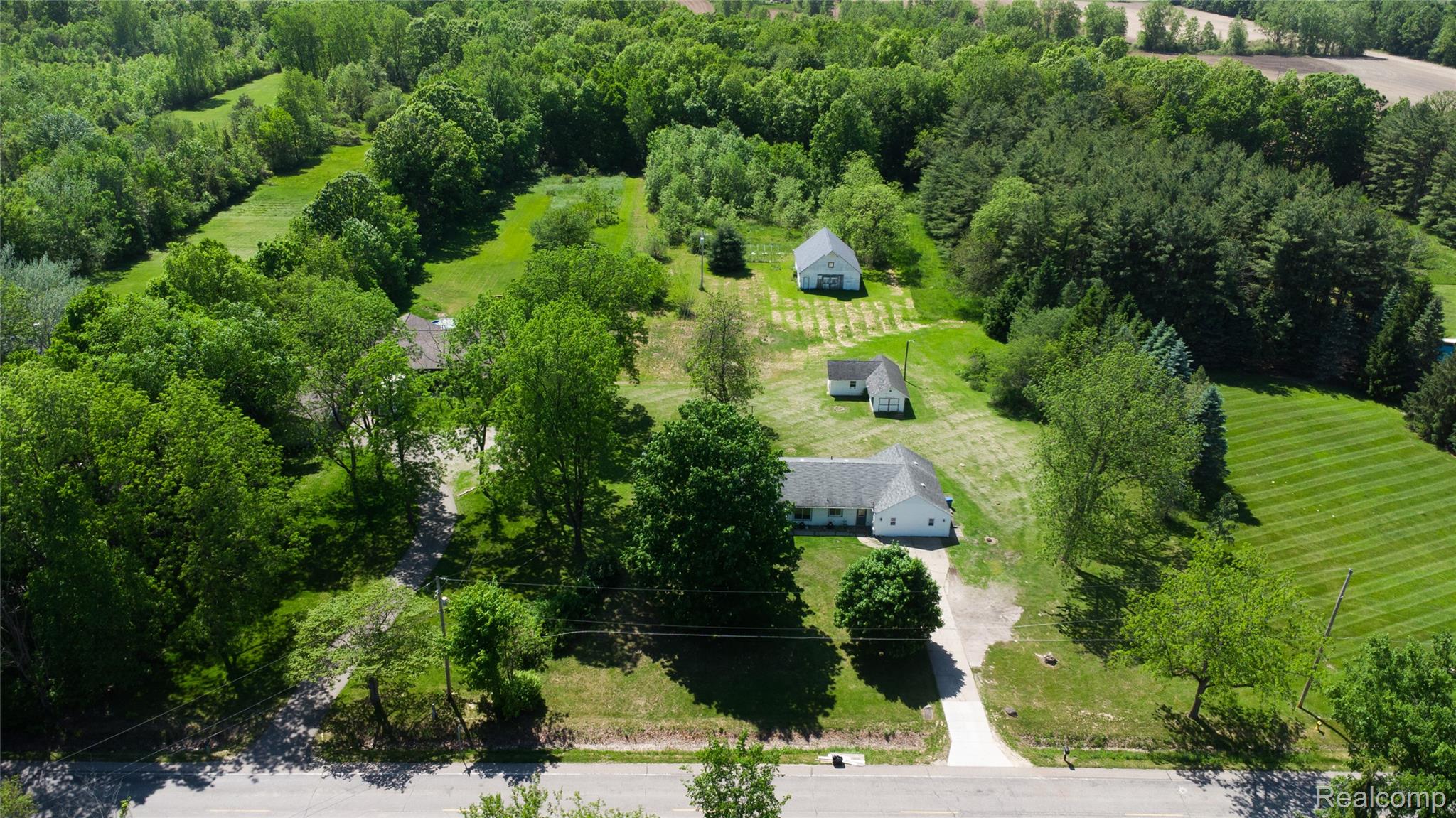 12238 Jennings Road Linden, MI 48451 - Photo 29 of 33 Expansive property featuring a main residence, two outbuildings, and a detached garage, all surrounded by mature trees and manicured lawns