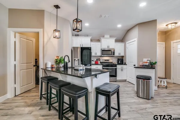 a kitchen with stainless steel appliances kitchen island granite countertop a refrigerator a stove a microwave oven a sink with a dining table and chairs