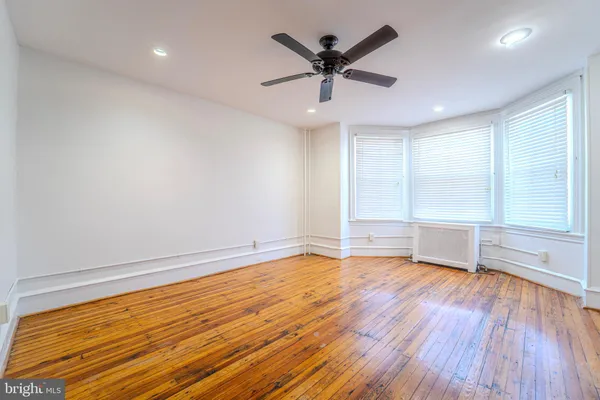 a view of empty room with wooden floor and fan