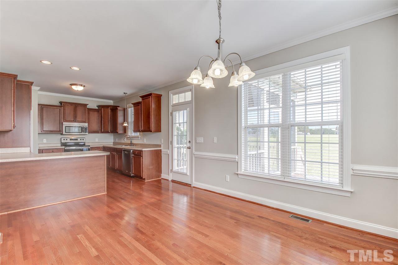 8905 Oregon Inlet Court Raleigh, NC 27603 - Photo 7 of 30 a large kitchen with kitchen island granite countertop a stove a sink dishwasher a refrigerator and white cabinets with wooden floor