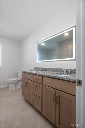 a bathroom with a granite countertop sink a toilet and mirror