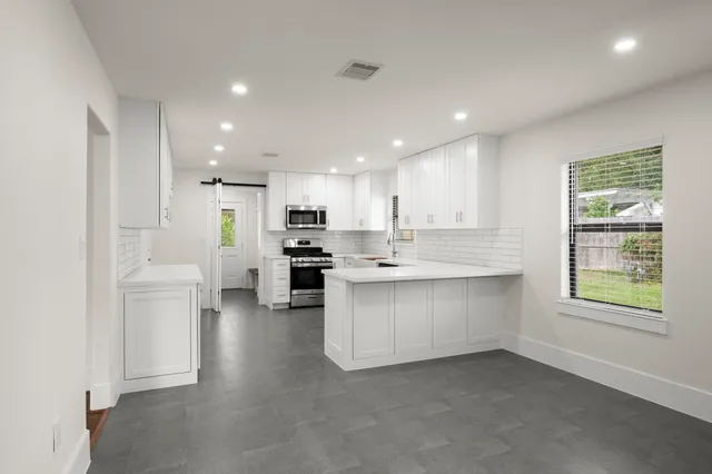 a kitchen with white cabinets and a window