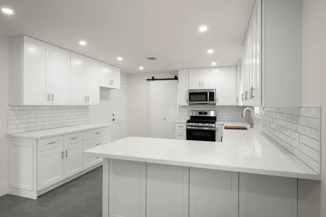 a kitchen with granite countertop a sink and white cabinets