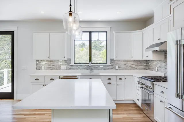 a kitchen with stainless steel appliances granite countertop a stove a sink dishwasher and white cabinets with wooden floor