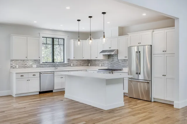 a large kitchen with stainless steel appliances a stove a sink a refrigerator a center island a stove and cabinets