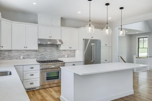 a large kitchen with stainless steel appliances a stove a sink a refrigerator a center island a stove and cabinets