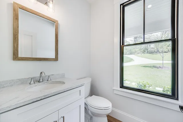 a bathroom with a granite countertop sink toilet and mirror