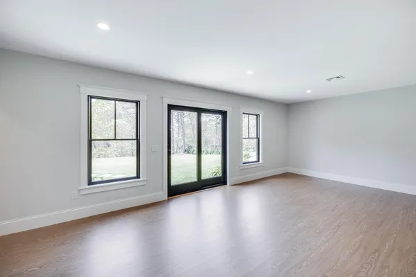 a view of an empty room with wooden floor and window