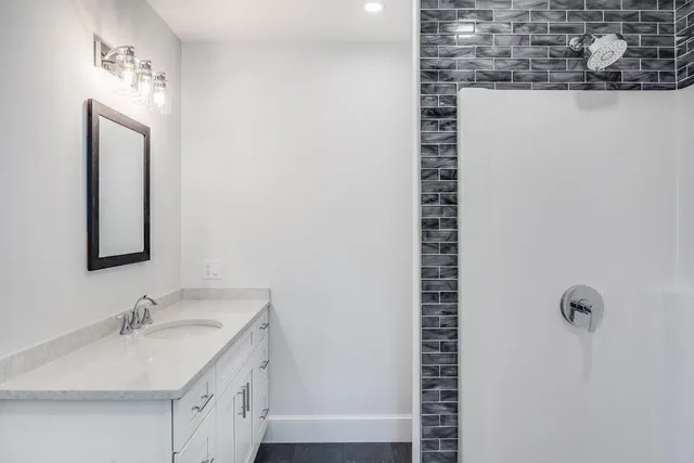 a bathroom with a granite countertop sink a mirror and shower