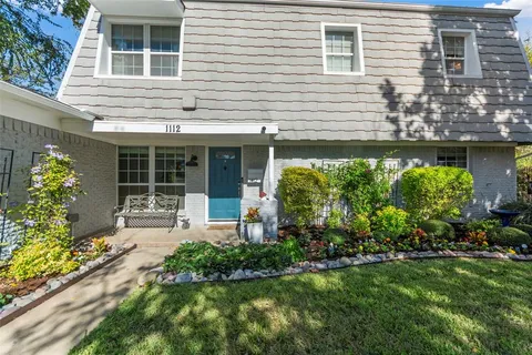 a front view of a house with a yard and potted plants