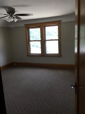 an empty room with a window and a ceiling fan
