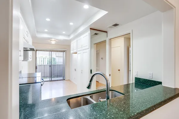 a kitchen with granite countertop a sink stainless steel appliances and white cabinets