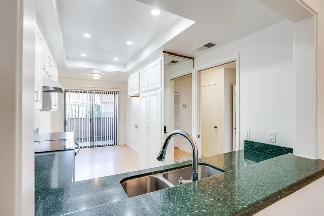 a kitchen with granite countertop a sink stainless steel appliances and white cabinets