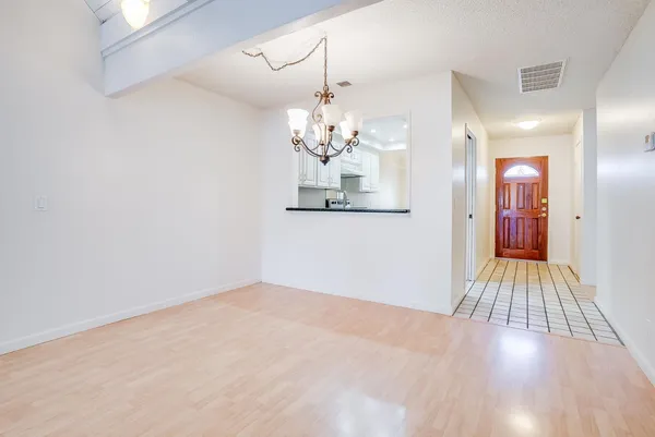 a view of an empty room with wooden floor and chandelier