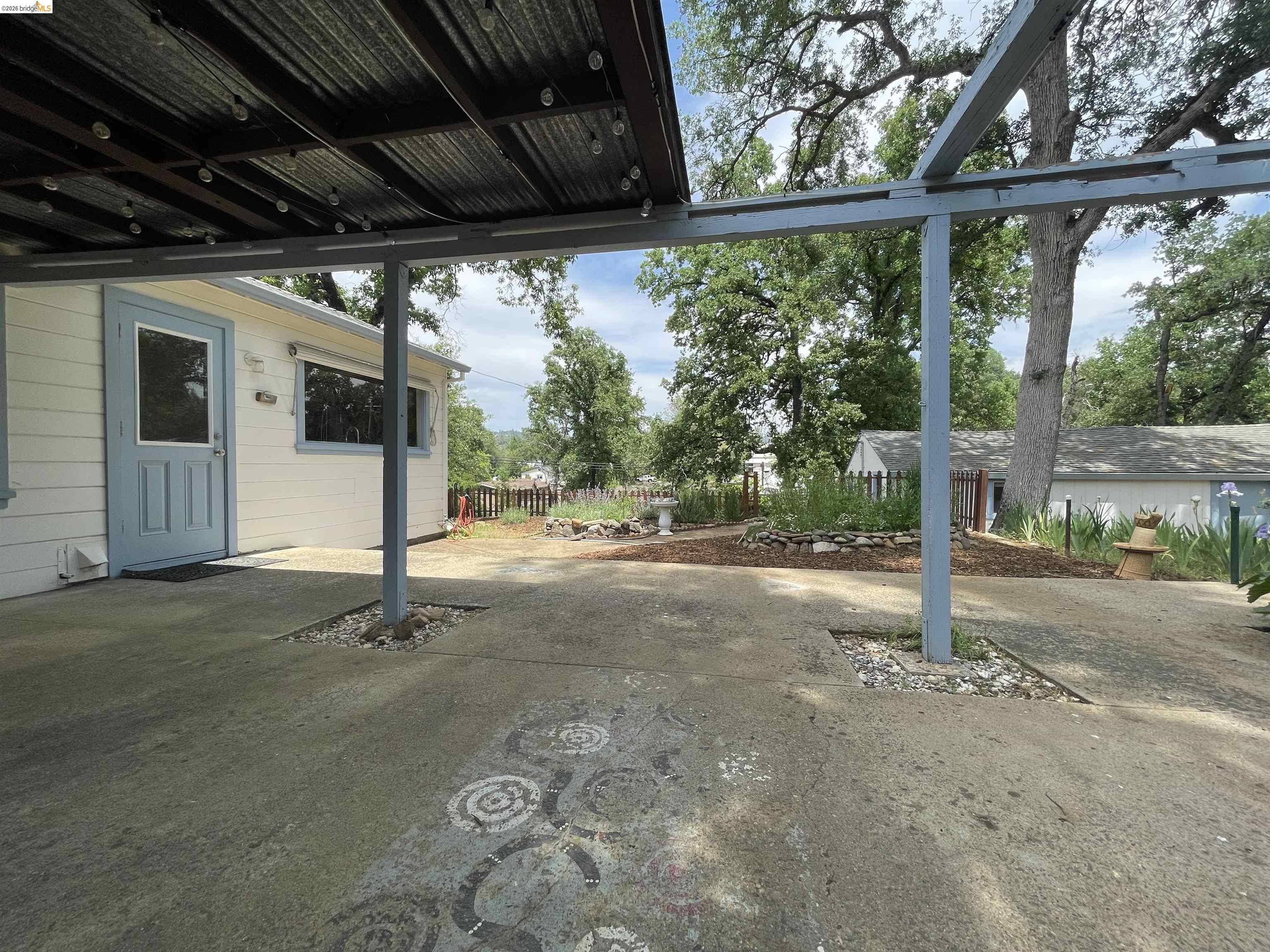 18363 Yosemite Road Tuolumne, CA 95379 - Photo 17 of 34 Covered outdoor patio with a corrugated metal roof and string lighting