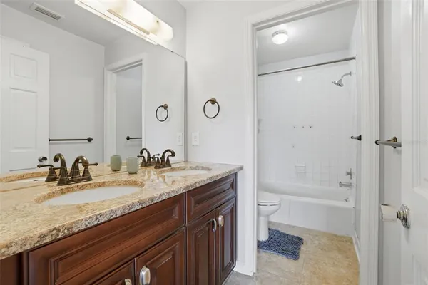 a bathroom with a granite countertop sink a toilet and shower