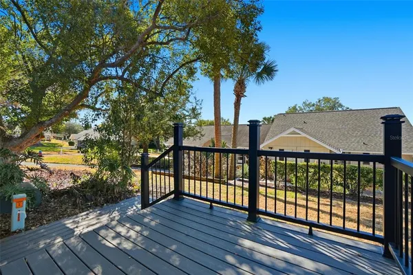 a view of a brick house with large trees and wooden fence