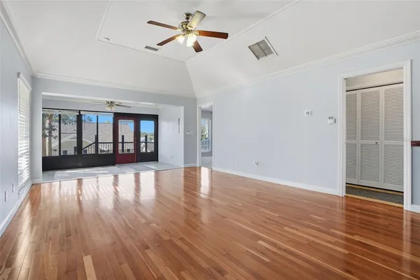 a view of an empty room with wooden floor and a window