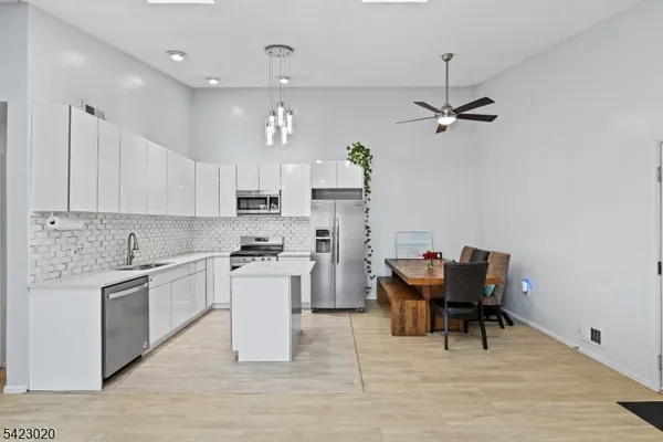 a kitchen with stainless steel appliances granite countertop a stove top oven a refrigerator a sink and chairs
