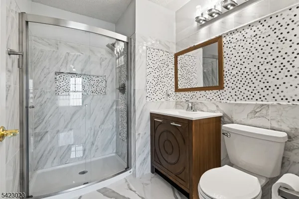 a bathroom with a toilet sink vanity mirror and shower