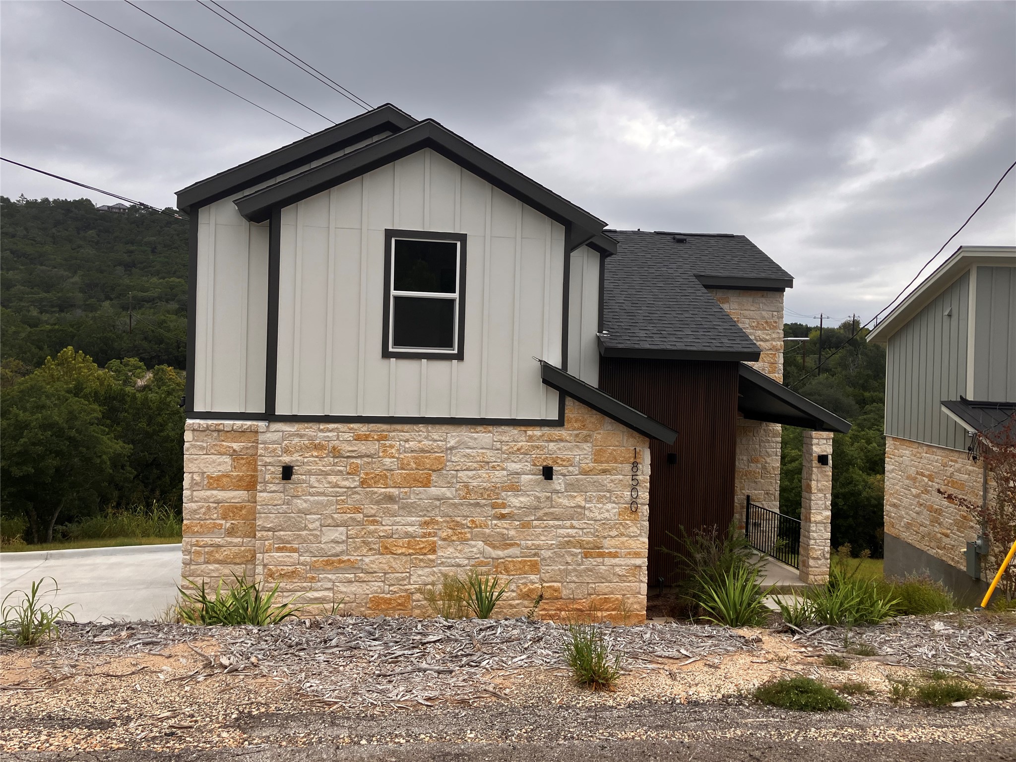 18500 Roundrock Road Jonestown, TX 78645 - Photo 1 of 1 View of home's exterior featuring stone siding, board and batten siding, and a shingled roof