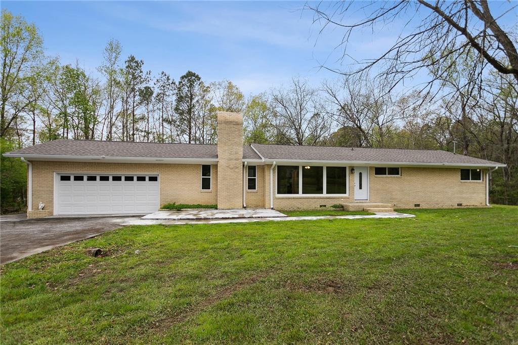 a front view of a house with a garden and trees