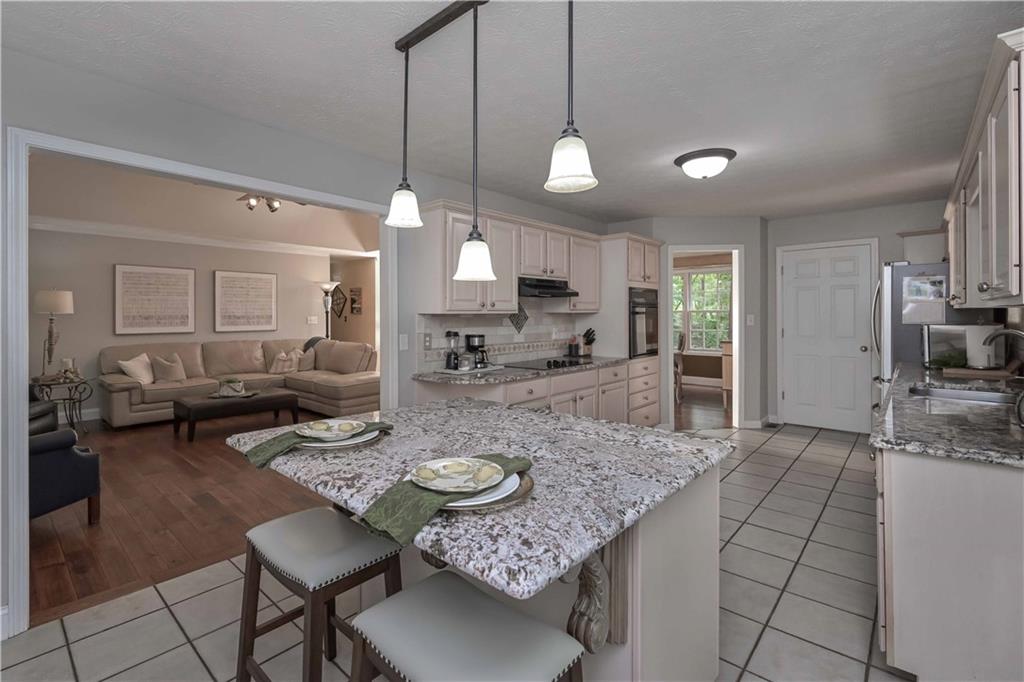 5885 West Chapel Hill Road Douglasville, GA 30135 - Photo 15 of 42 a open kitchen with stainless steel appliances granite countertop a stove a sink a dining table and chairs with wooden floor