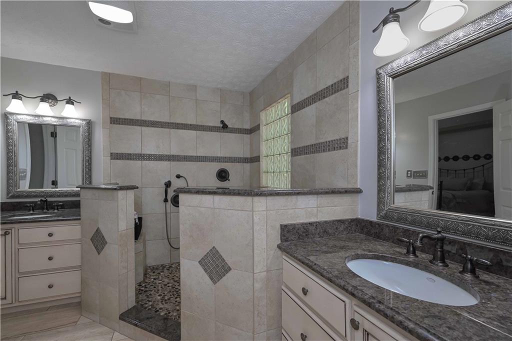 5885 West Chapel Hill Road Douglasville, GA 30135 - Photo 28 of 42 a bathroom with a granite countertop sink a mirror and shower