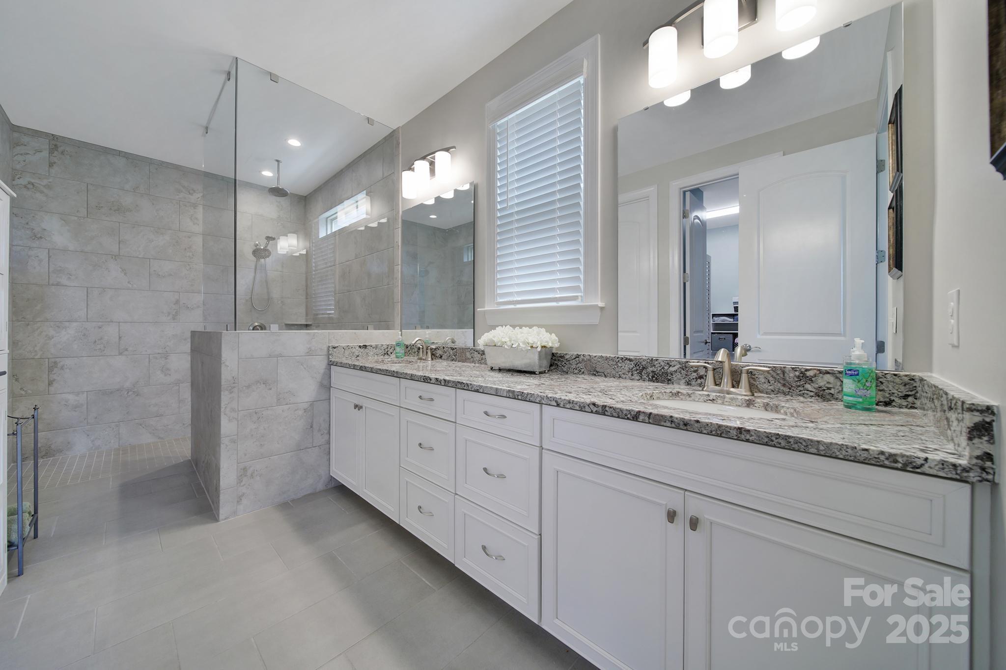 537 Lincoln Quarters Lane Fort Mill, SC 29708 - Photo 19 of 42 a bathroom with a granite countertop double vanity sink a mirror and a shower