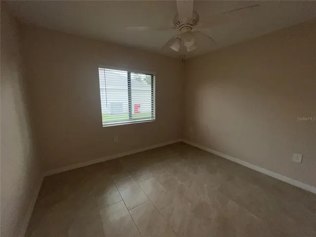 an empty room with a ceiling fan and a window