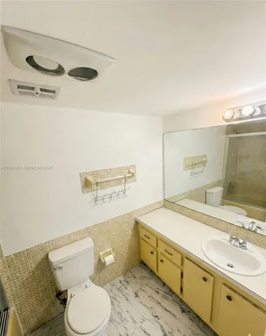 a bathroom with a granite countertop toilet and a sink