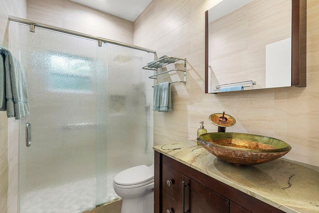 a bathroom with a granite countertop sink a toilet and shower