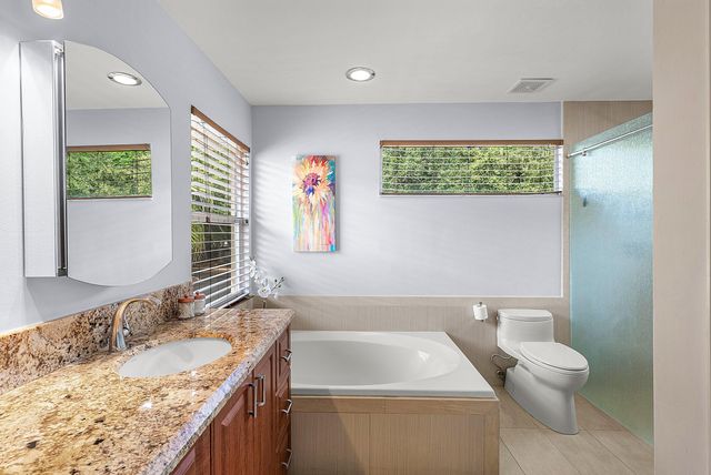 a bathroom with a granite countertop sink a toilet a mirror and a window