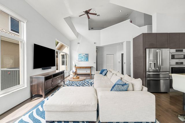 a living room with stainless steel appliances furniture and a flat screen tv