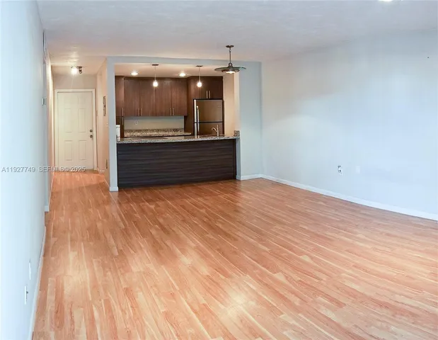 a view of kitchen and empty room with wooden floor