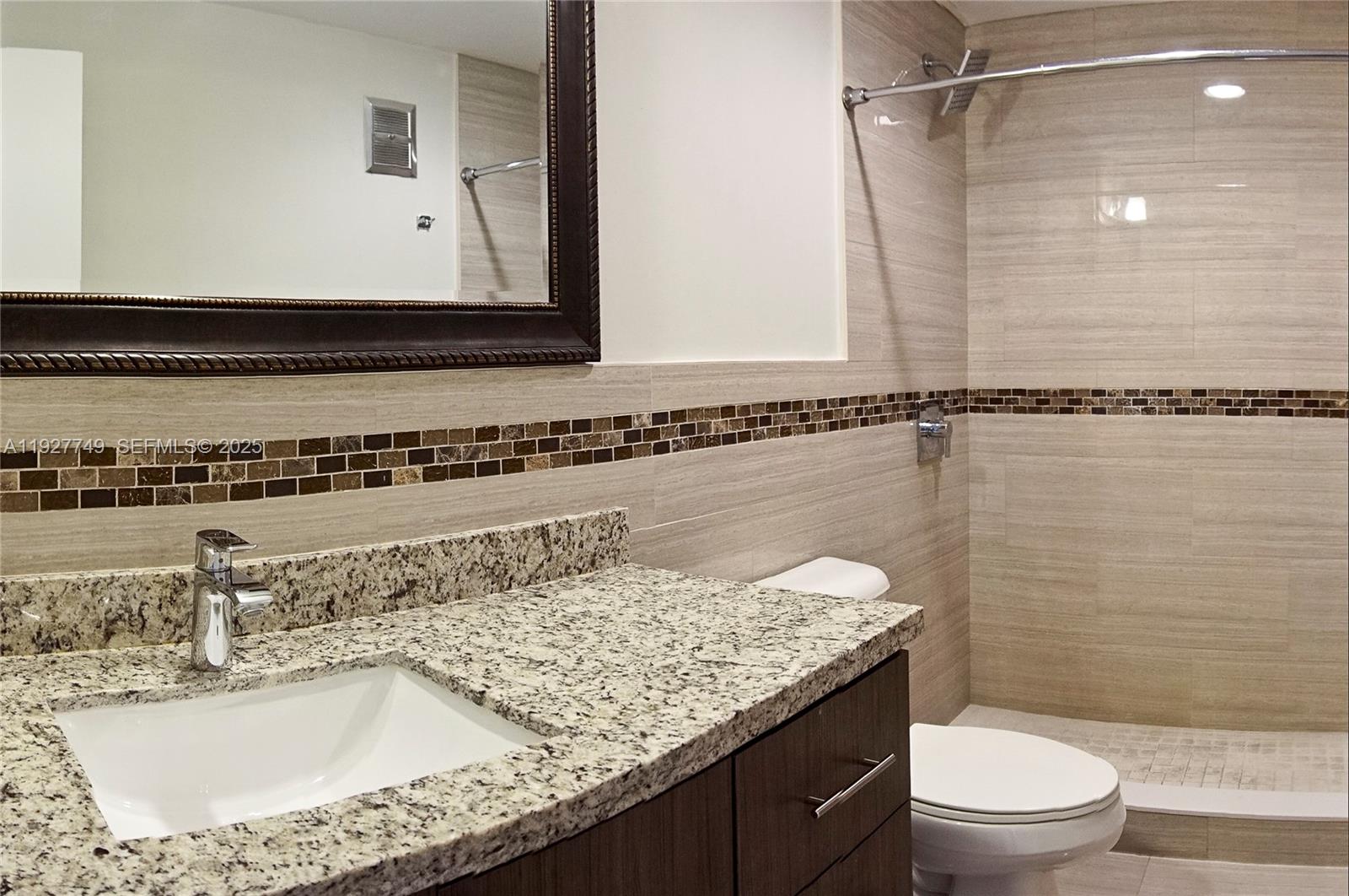9651 Southwest 77th Avenue, Unit 304E Miami, FL 33156 - Photo 13 of 19 a bathroom with a granite countertop sink a toilet and shower