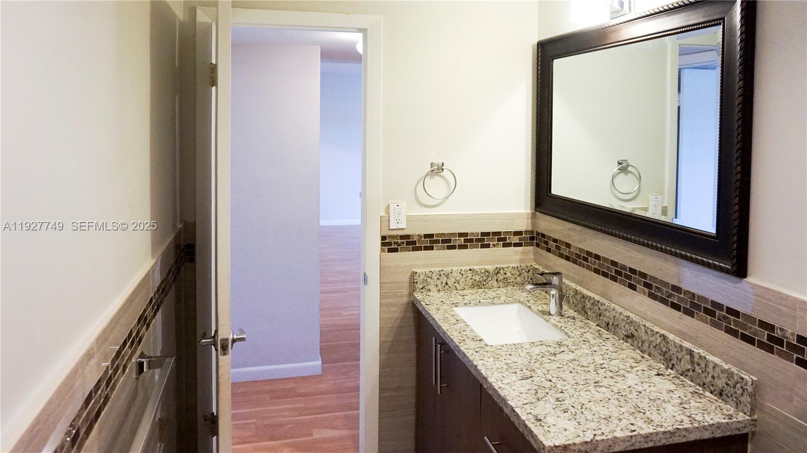 9651 Southwest 77th Avenue, Unit 304E Miami, FL 33156 - Photo 17 of 19 a bathroom with a granite countertop sink and mirror