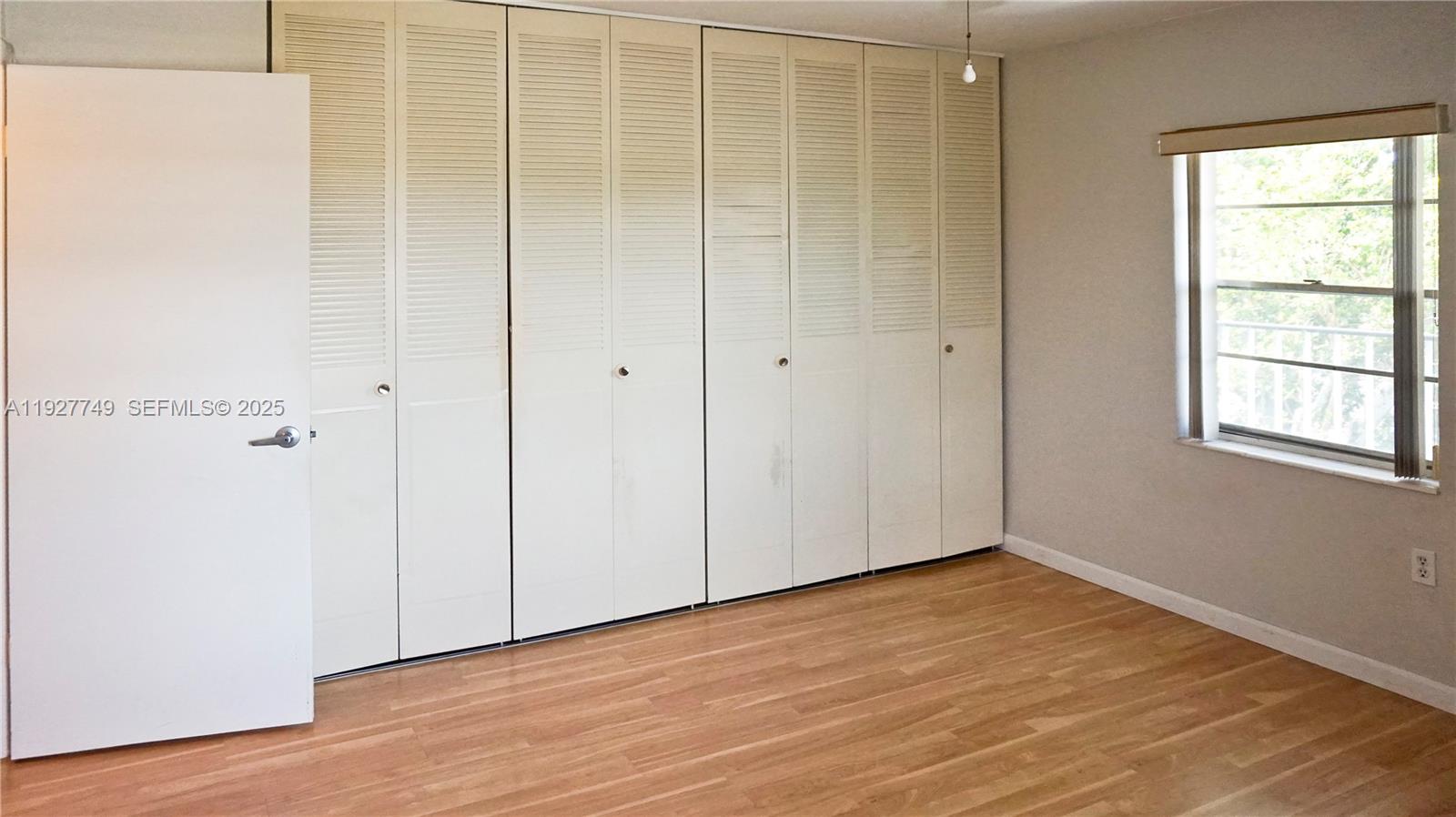 9651 Southwest 77th Avenue, Unit 304E Miami, FL 33156 - Photo 18 of 19 a view of an empty room with wooden floor and a window