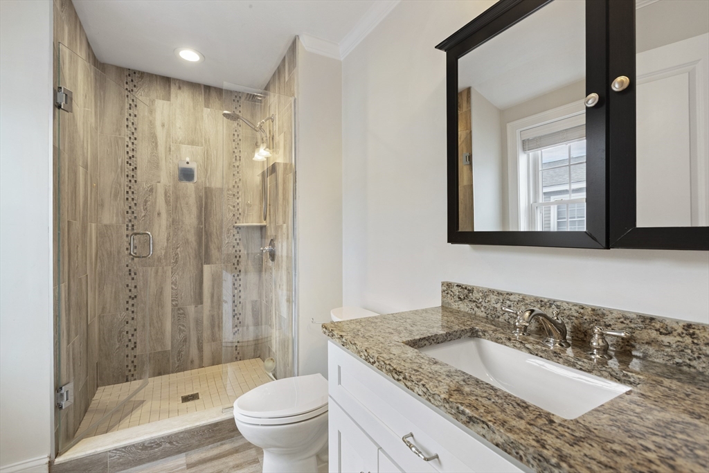 113 Elm Street, Unit D Quincy, MA 02169 - Photo 19 of 39 a bathroom with a granite countertop sink a toilet a mirror and shower
