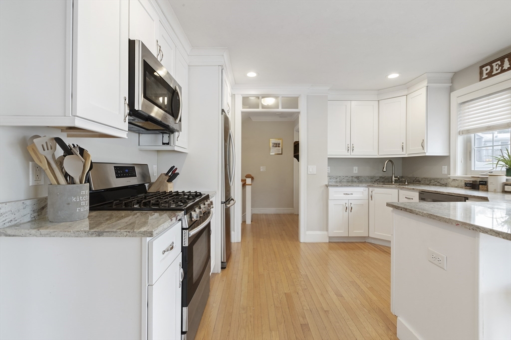 113 Elm Street, Unit D Quincy, MA 02169 - Photo 6 of 39 a kitchen with stainless steel appliances granite countertop a stove top oven a sink a refrigerator white cabinets and wooden floor
